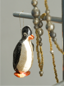 Penguin ornament hanging among beads on a stand