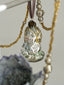 Decorative hanging ornament with beads and a small figurine on a neutral background