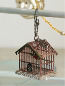 Decorative birdhouse ornament hanging on a metal rod with a blurred background