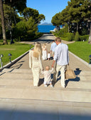 Family Business in Christmas Ornaments, Family walking along a path by a scenic coastal area with trees and water in the background.